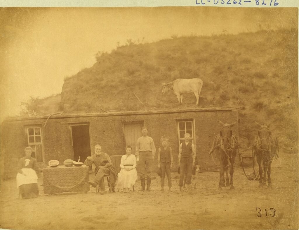 Pioneer family posing in front of a sod house in Custer County, Nebraska, 1886