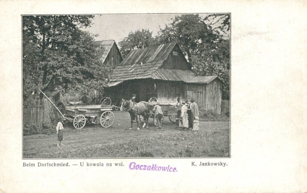 Old postcard of a village blacksmith's shop with a horse cart outside a wooden building